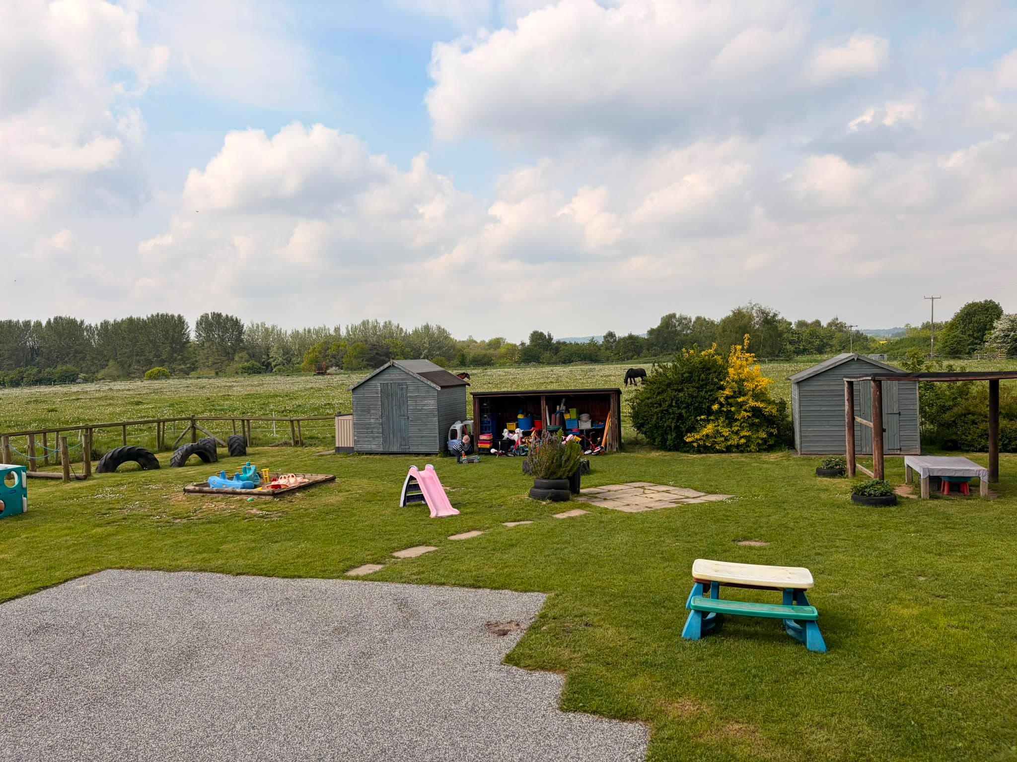 Nursery outdoor grounds with play sheds, picnic bench and slide, overlooking open Shropshire countryside